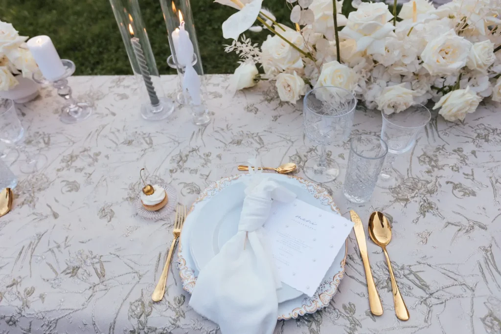 A beautifully set dinner table with white roses, elegant tableware, and a menu card, prepared for an intimate elopement celebration at Medvedgrad Castle in Zagreb.