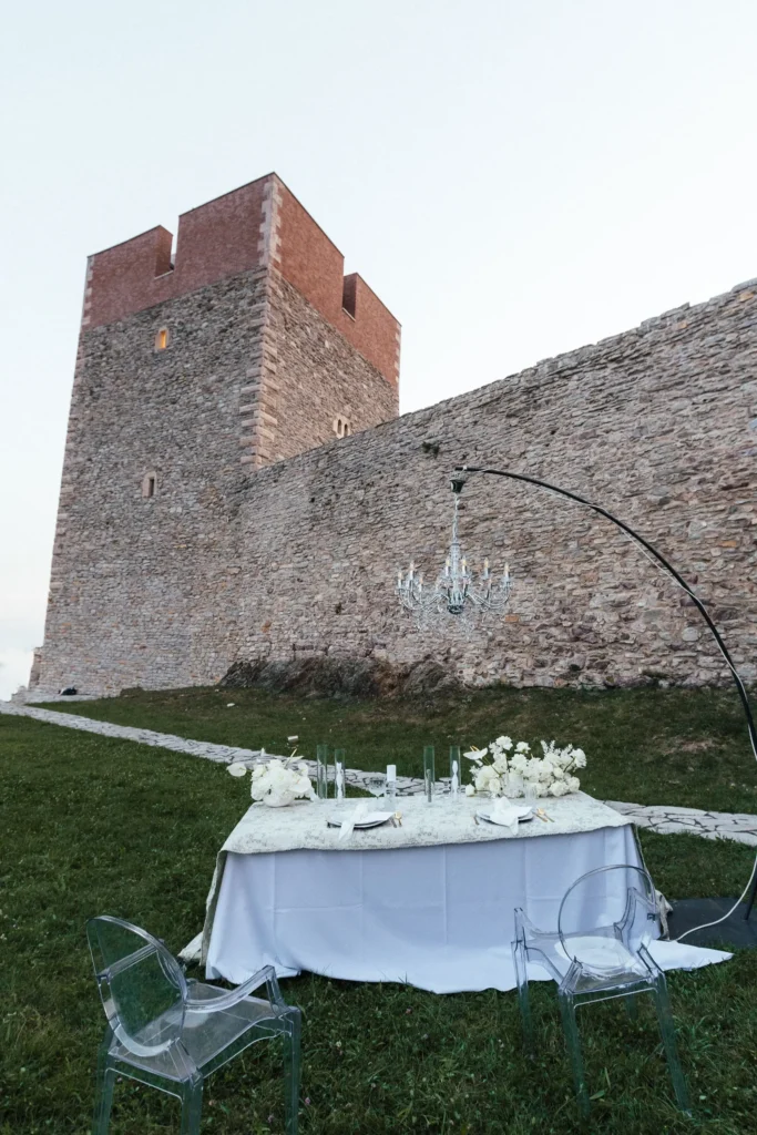 A beautifully set table for an intimate elopement dinner at the foot of Medvedgrad Castle in Zagreb, with a chandelier hanging above.