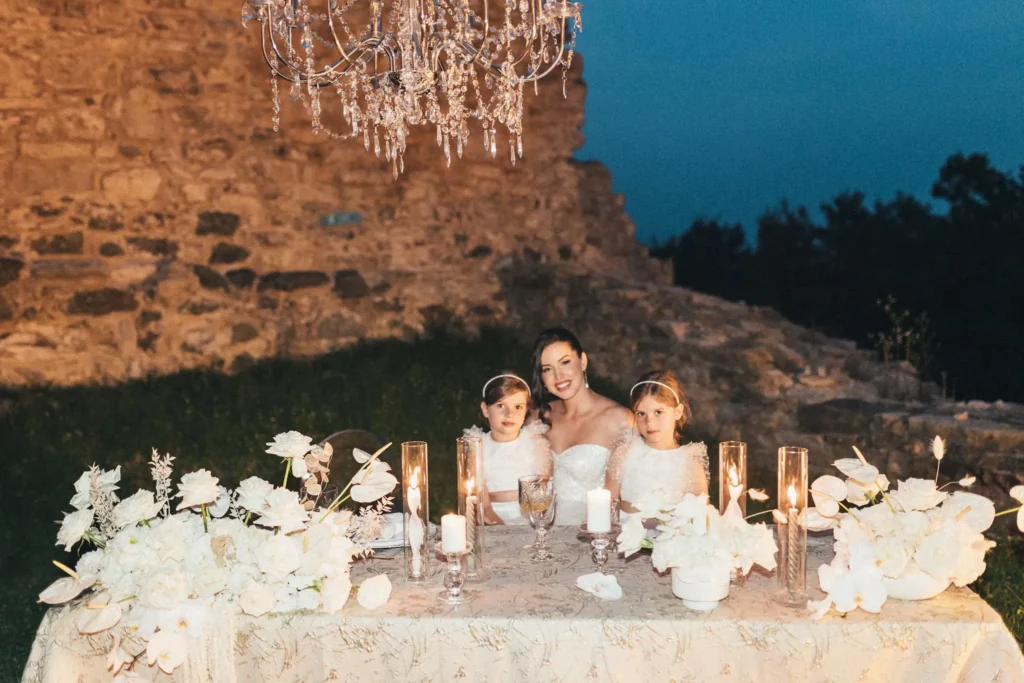 At Medvedgrad Castle in Zagreb, the bride and her bridesmaids find themselves at an elegantly set table during their elopement celebration. Adorned with white flowers and candles under a chandelier, the scene radiates an intimate and charming atmosphere.