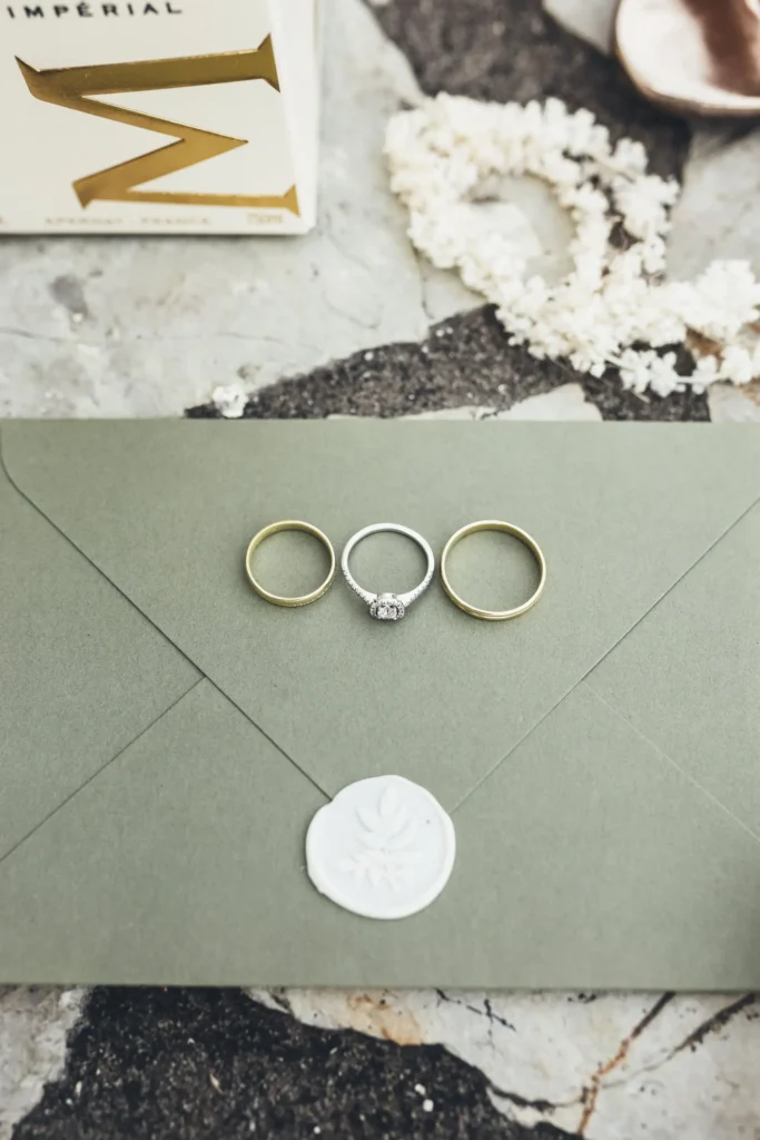 Three wedding rings displayed on a green envelope, symbolizing the vows exchanged during an intimate elopement ceremony at Medvedgrad, Zagreb.